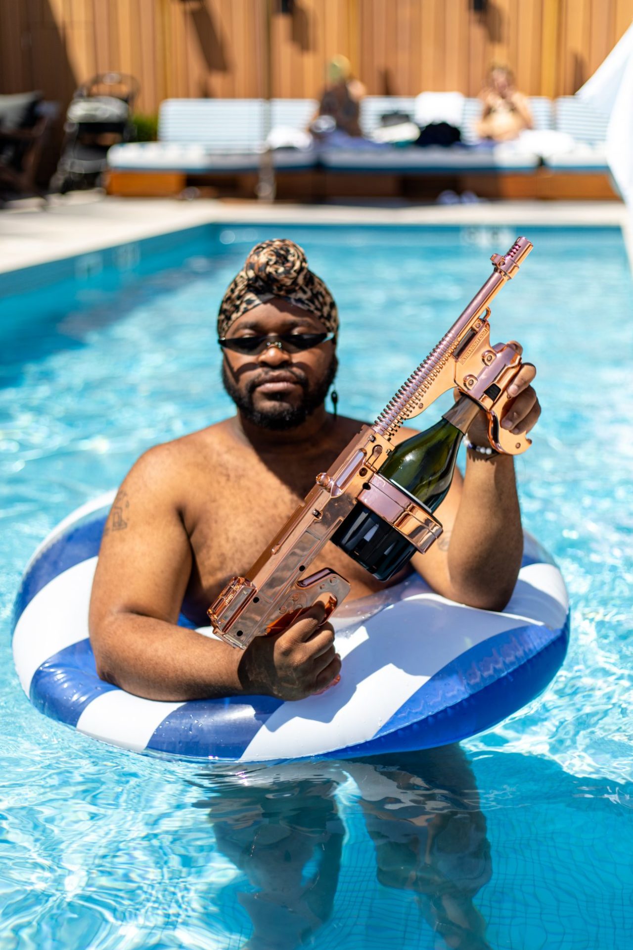 Male in a tube in the rooftop pool at the Clayton hotel holding a gun shaped device with a champagne bottle loaded in it