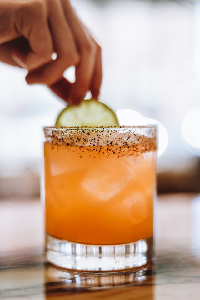 Orange colored drink with a lime slice served at the Of A Kind Bar in Denver